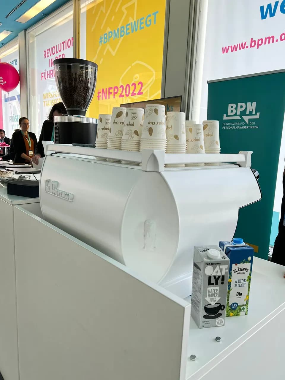 Weiße La-Marzocco-Siebträgermaschine und Mahlkönig-Mühle auf einer mobilen Bar an einem Messestand