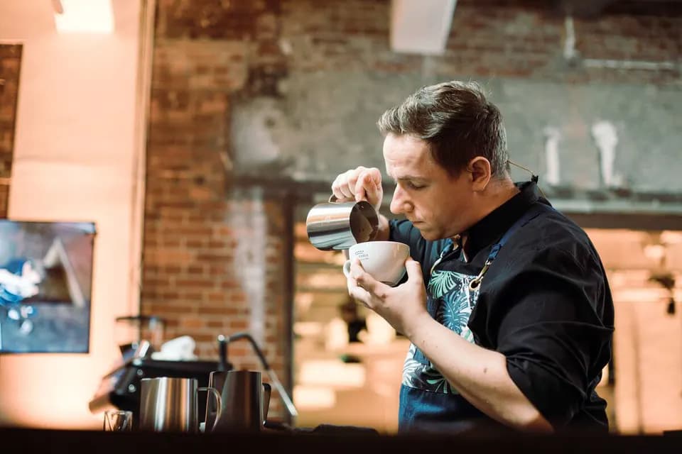 Kai Mößner gießt Milchschaum in eine Tasse