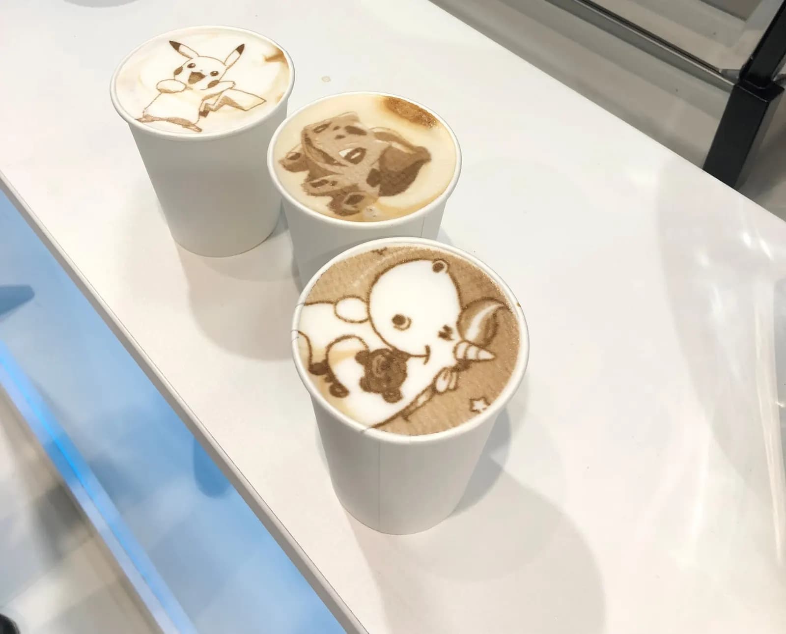 Drei Kaffeebecher mit gedruckten Motiven im Milchschaum