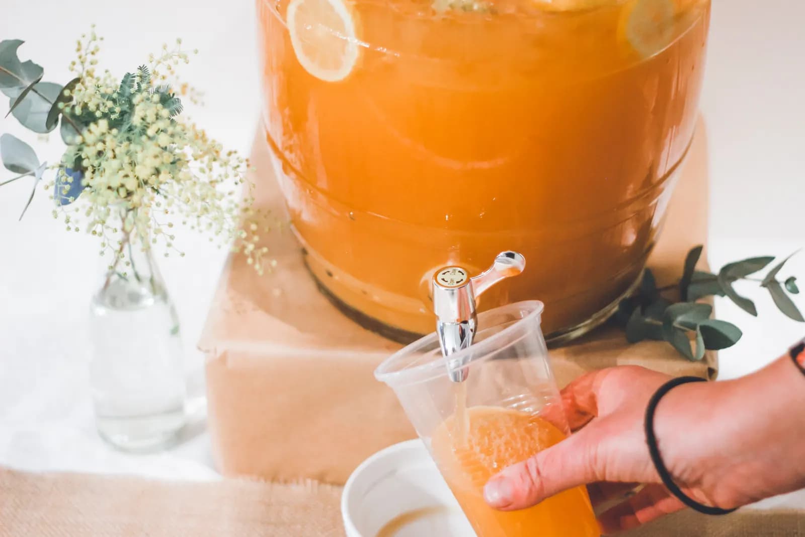 Orangensaft wird aus einem Glasbehälter mit Zapfhahn gezapft